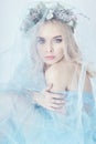 Charming fairy woman in a blue ethereal dress and a wreath on her head on white background, gentle mysterious blonde girl Royalty Free Stock Photo