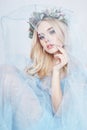 Charming fairy woman in a blue ethereal dress and a wreath on her head on white background, gentle mysterious blonde girl Royalty Free Stock Photo