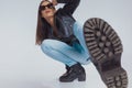 Charming fashion model adjusting sunglasses and kicking with her leg