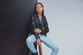 Charming fashion model wearing leather jacket while sitting Royalty Free Stock Photo