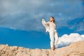 charming fashionable model in white trendy clothes with silk scarf walking