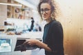 Charming fashionable woman with eyes glasses reading magazine sitting indoor in urban cafe.Casual portrait of pretty