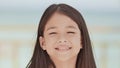 A charming filipino schoolgirl positively poses. Face close-up on a white-blue background of a tropical beach.