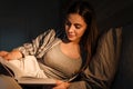 Charming focused woman reading book while lying in bed at home