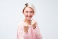 Charming funny caucasian woman in pink sweater raising fists, standing in boxer pose, wanting to punch friend