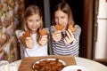 Charming, funny and laughing girls on a blurry background are holding heart-shaped cookies on an outstretched arm, two hearts Royalty Free Stock Photo