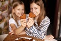 Charming, funny and laughing girls on a blurry background are holding heart-shaped cookies on an outstretched arm, two hearts Royalty Free Stock Photo