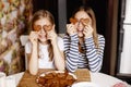 Charming, funny and laughing girls hold heart-shaped cookies, close their eyes and fool around