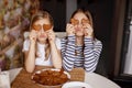 Charming, funny and laughing girls hold heart-shaped cookies, close their eyes and fool around