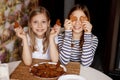 Charming, funny and laughing girls hold heart-shaped cookies, close their eyes and fool around