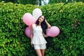 Charming girl with balloons in green hedgerow Royalty Free Stock Photo
