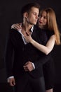 A charming girl in a black dress strokes her man`s chest through an unbuttoned shirt Royalty Free Stock Photo