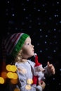 Charming girl Christmas Santa hat black background with star lanterns. portrait todller against starry sky. Royalty Free Stock Photo