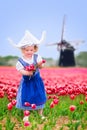 Charming Girl In Dutch Costume In Tulips Field With Windmill