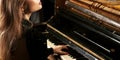 Charming girl in a green dress enjoys playing the retro piano