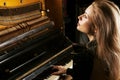 Charming girl in a green dress enjoys playing the retro piano