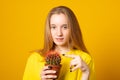 Charming girl holding green cactus pot isolated yellow color background Royalty Free Stock Photo