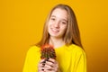 Charming girl holding green cactus pot isolated yellow color background Royalty Free Stock Photo