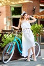 Charming girl leans against vintage bicycle near summer street cafe Royalty Free Stock Photo