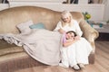 Charming girl lying on mother`s knees on sofa