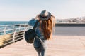 Charming girl photographer with long hair and a stylish backpack taking photo of delightful seascape. Young brunette Royalty Free Stock Photo