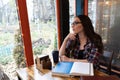 Charming girl study at campus cafe wearing glasses and open books, notes in front of her. Young student girl in casual Royalty Free Stock Photo