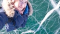 A charming girl takes a selfie on her smartphone with her hand stretched out against the background of a bright frozen lake Baikal