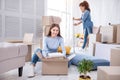 Charming girl unpacking books while her friend cleaning floor Royalty Free Stock Photo