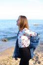 Charming girl walks along coast and merrily fools around on sand Royalty Free Stock Photo