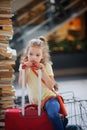 Charming girlie 7-8 years sits beside their luggage at the station. Royalty Free Stock Photo