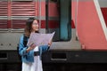 Charming glasses Asian woman standing side an old train holding a map before start to go in travel at train station Royalty Free Stock Photo