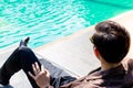 Charming handsome young businessman sits near swimming pool for