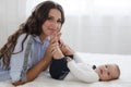 Charming happy little baby boy having fun with mom brunette woman on bed in the bright bedroom Royalty Free Stock Photo