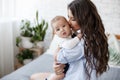 Charming happy little baby boy having fun with mom brunette woman on bed in the bright bedroom Royalty Free Stock Photo