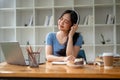 A charming Asian female college student enjoys music on her headphones at her study table Royalty Free Stock Photo
