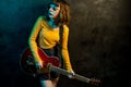 Charming hipster woman with curly hair with red guitar in neon lights. Rock musician is playing electrical guitar. 90s Royalty Free Stock Photo