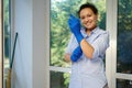 Charming housewife maid, homemaker putting on blue rubber work gloves to clean the house. Housekeeping. Chores. Cleaning Royalty Free Stock Photo