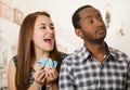 Charming interracial couple holding up small letters spelling the say while interacting happily, blurry studio Royalty Free Stock Photo
