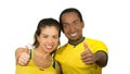 Charming interracial couple wearing yellow football shirts giving thumbs up to camera, white studio background Royalty Free Stock Photo
