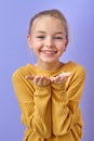 charming kid girl 12-13 years old in yellow shirt blow air kiss isolated on purple Royalty Free Stock Photo