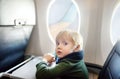 Afraid little boy sitting by aircraft window during the flight