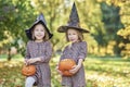 Charming kids in witch costume holding halloween pumpkins