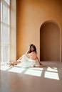 Charming lady with dark hair sitting on floor near window