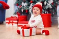 Charming toddler boy holds white christmas gift box with red ribbon. Funny cute baby weared in festive clothes in Royalty Free Stock Photo