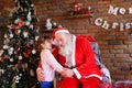 Little girl hugs Santa Claus and makes wish for Christmas in coz Royalty Free Stock Photo