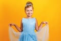 Charming little girl in a costume of Princess Cinderella on a yellow colored background. Royalty Free Stock Photo