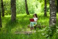 Charming little girl in forest with book sitting on tree stump Royalty Free Stock Photo