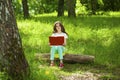 Charming little girl in forest with book sitting on tree stump Royalty Free Stock Photo