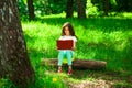 Charming little girl in forest with book sitting on tree stump Royalty Free Stock Photo