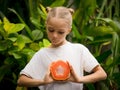 Charming little girl with fresh papaya. Caucasian girl holding slice of papaya fruit in front of her chest. Selected focus. Green Royalty Free Stock Photo